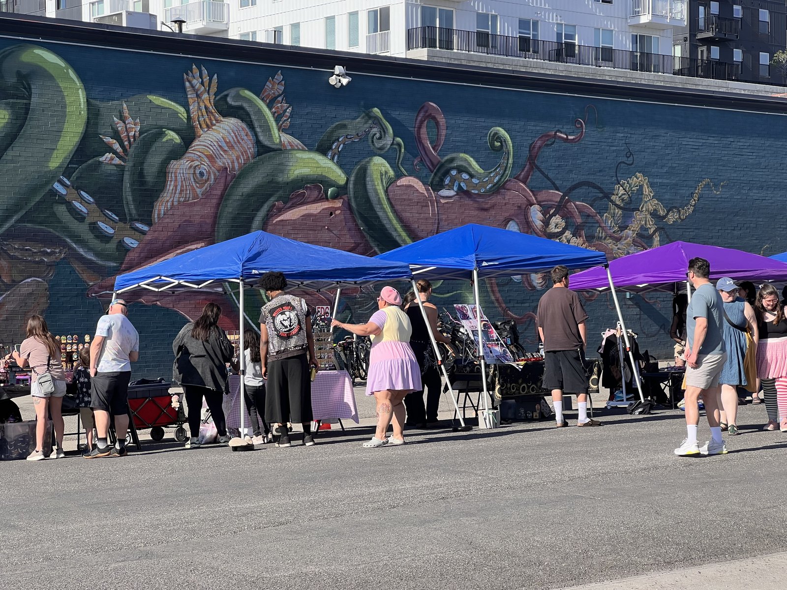 Vendor tents set up in front of a large octopus mural at South Salt Lake Mural Fest 2026